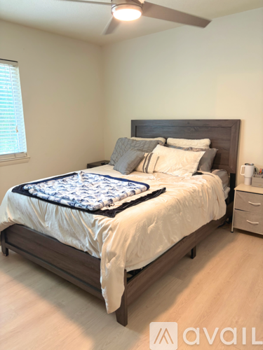 A bedroom with a bed, nightstand, and window.