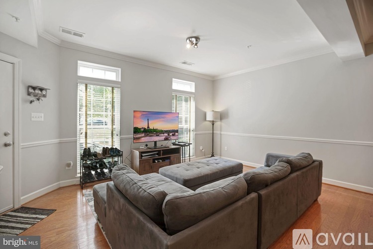 A living room with a grey couch and a painting on the wall.