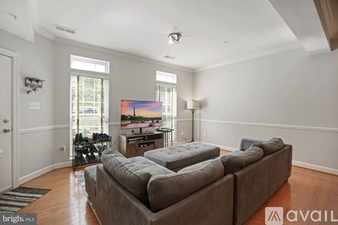 A living room with a grey couch and a painting on the wall.