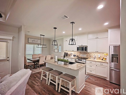 A kitchen with a white island and a dining table with chairs.