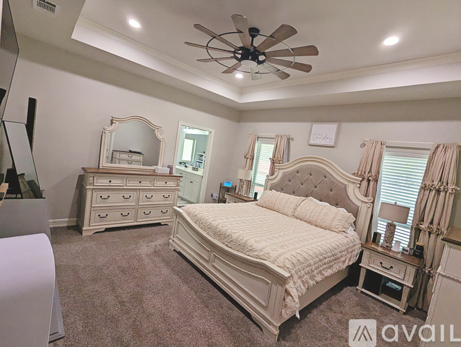A bedroom with a large bed, dresser, and mirror.