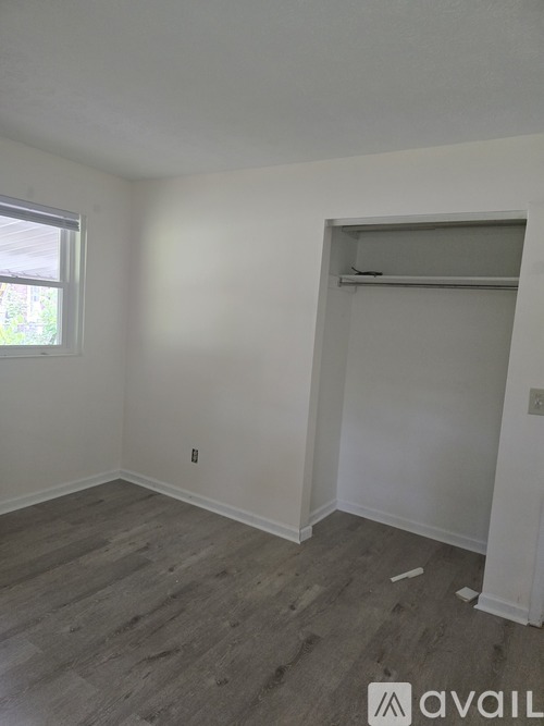 A room with a window and a wooden floor.