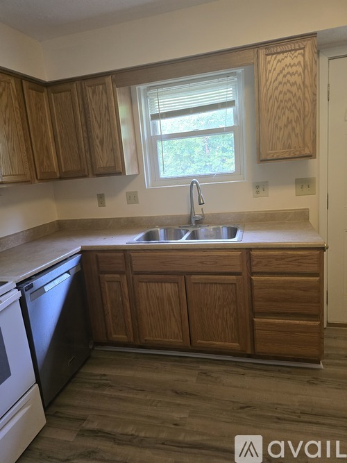 A kitchen with wooden cabinets and a black dishwasher.
