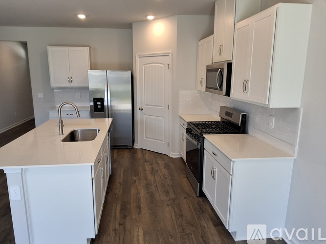 A kitchen with white cabinets and a wooden floor.