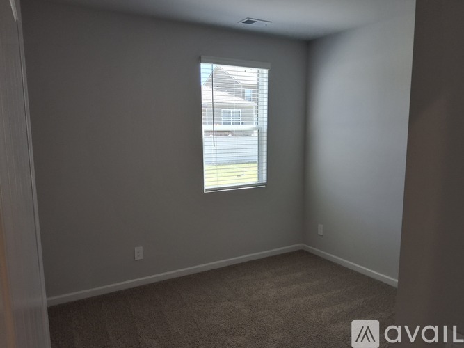A room with a carpeted floor and a window showing a building outside.