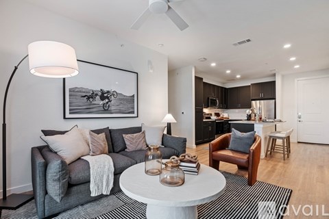 A modern living room with a grey couch, a round table, and a painting of a motorcycle on the wall.