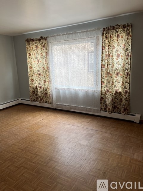 A room with a window covered by floral curtains.