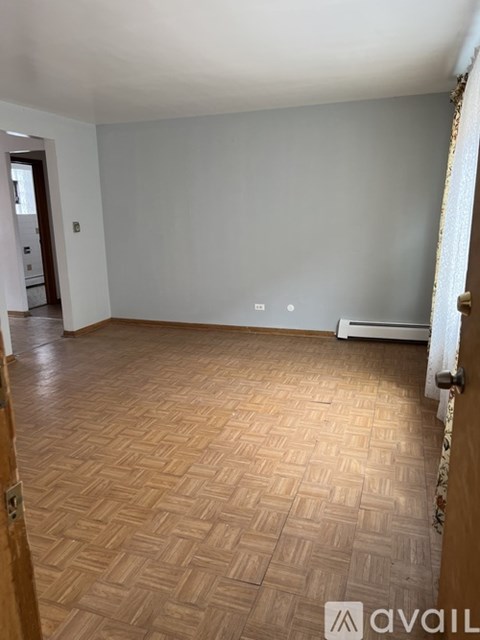 A room with wooden flooring and a white wall.