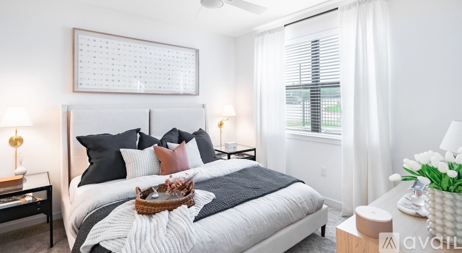 A bedroom with a large bed, a nightstand with a lamp, and a vase of tulips on the side table.