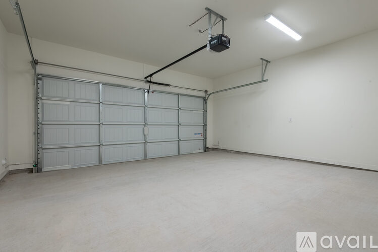 A spacious garage with a closed white door and a hanging light fixture.