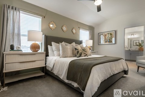 A well-lit bedroom with a large bed and a nightstand with a lamp.