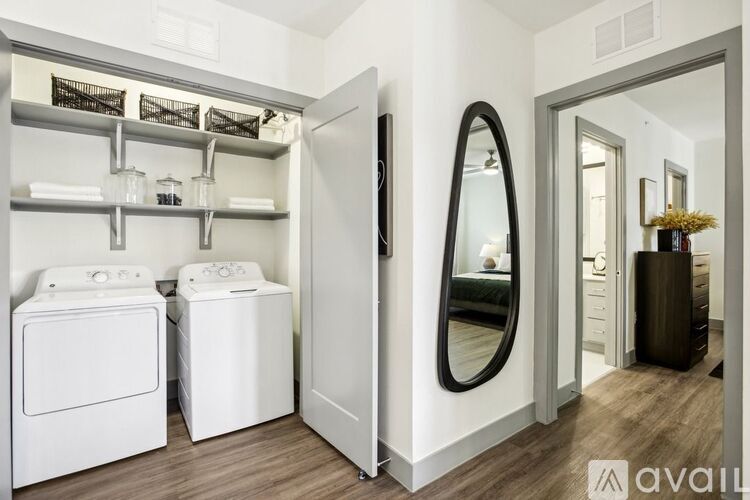 A laundry room with a washer and dryer, a mirror, and a wooden floor.