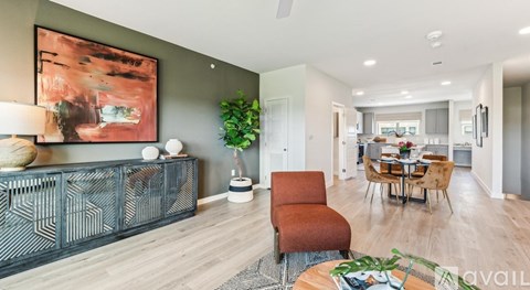 A living room with a red chair and a painting on the wall.