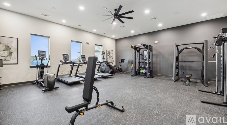 A well-equipped gym with a variety of exercise machines and a ceiling fan.