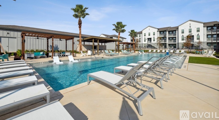 A pool with sun loungers and palm trees in front of a building.