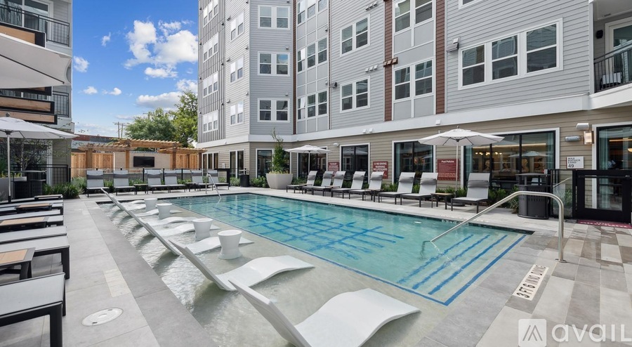 A large outdoor swimming pool surrounded by lounge chairs and umbrellas.