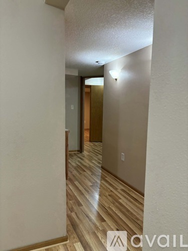 A hallway with wood flooring and white walls.