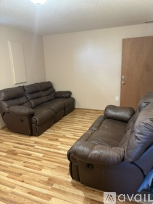 A living room with a brown leather couch and a brown leather recliner.