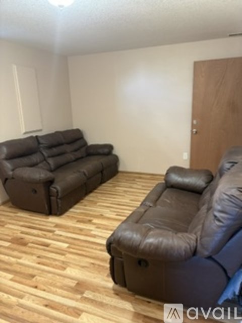 A living room with a brown leather couch and a brown leather recliner.