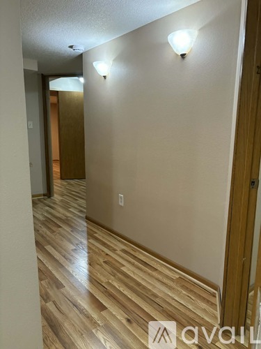 A hallway with wood flooring and two wall lights.