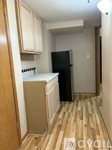A kitchen with wooden floors and a black refrigerator.