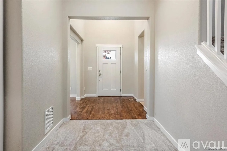 A hallway with a door at the end and a carpet on the floor.