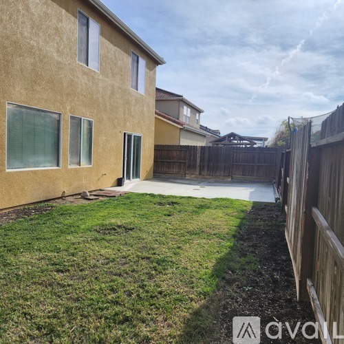 A house with a brown exterior and a white door is surrounded by a wooden fence.