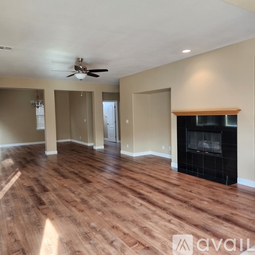 A spacious room with a fireplace and wood flooring.