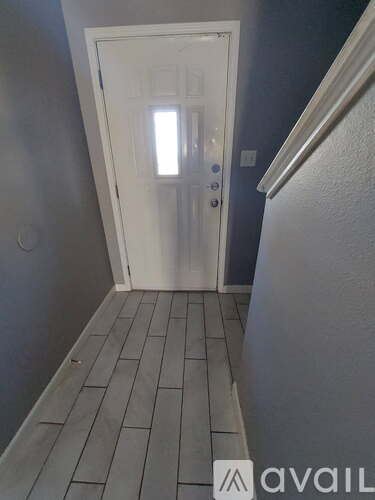 A hallway with a white door and tiled floor.