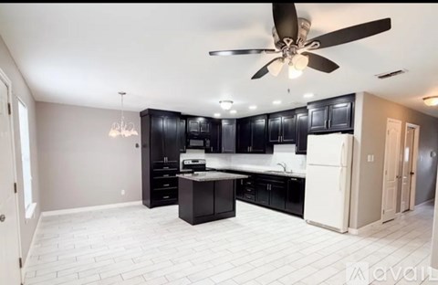 A kitchen with black cabinets and a white refrigerator.