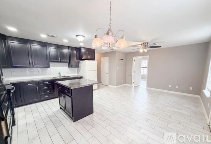 A kitchen with black cabinets and a white tiled floor.