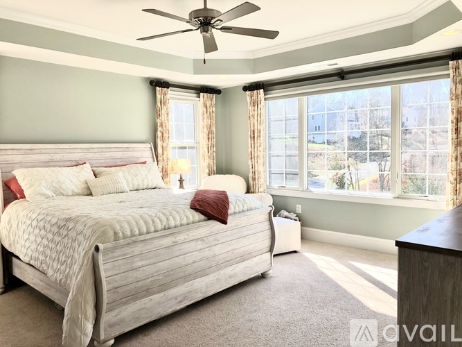A bedroom with a large bed and a ceiling fan.