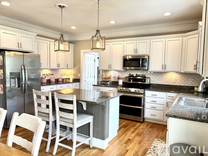 A kitchen with white cabinets and a black fridge.