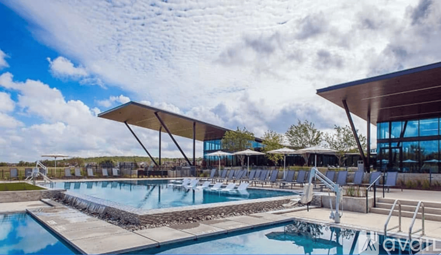A large outdoor swimming pool with a sunshade over it.