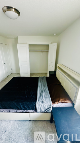 A bedroom with a bed and a bench in the corner.