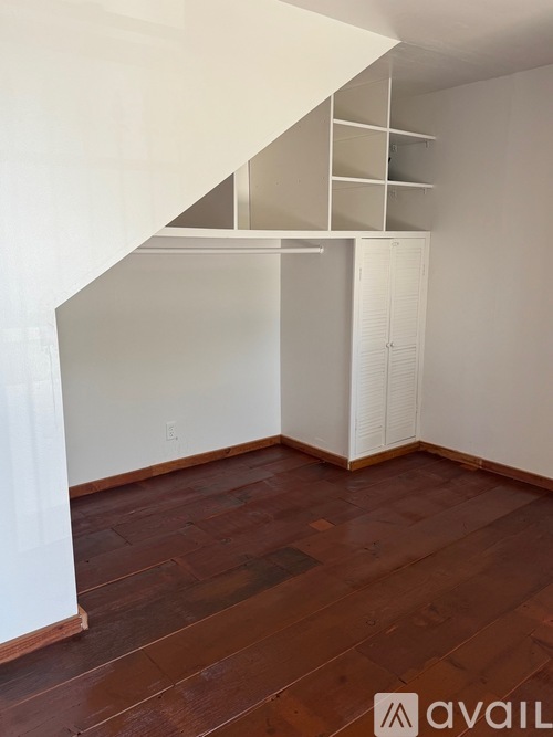 A room with a white wall and a wooden floor.