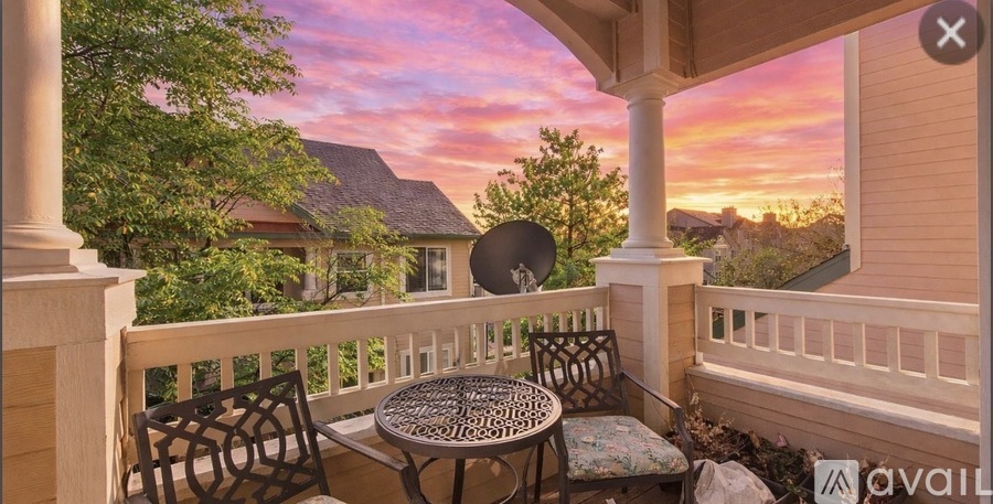 A balcony with a table and chairs overlooking a residential area.
