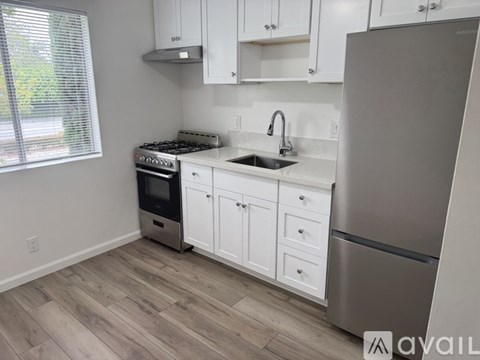 A kitchen with white cabinets and a stainless steel refrigerator.