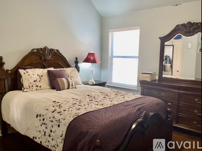 A bedroom with a large bed and a wooden dresser.