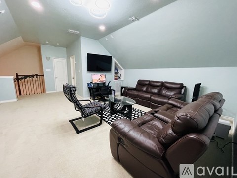 A living room with a brown leather couch and a television.