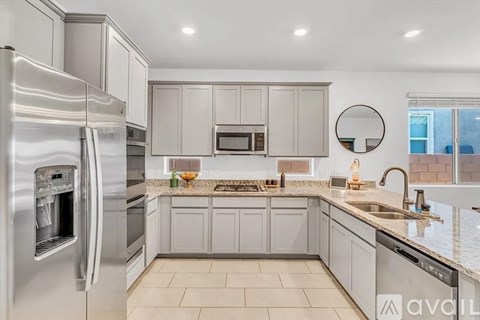 A modern kitchen with a stainless steel refrigerator and a marble countertop.