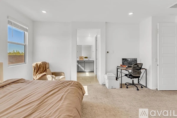 A bedroom with a large bed and a desk with a chair.