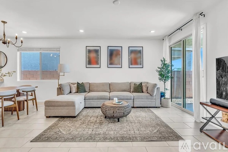A living room with a grey sofa, a coffee table, and a chandelier.