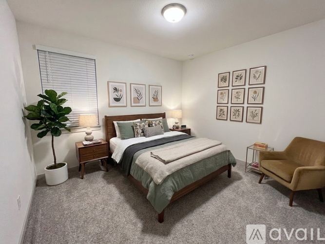 A bedroom with a bed, chair, and pictures on the wall.