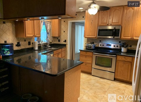 A kitchen with wooden cabinets and black countertops.