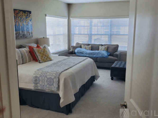 A bedroom with a bed, a couch, and a painting on the wall.