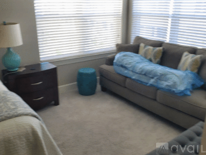 A living room with a grey couch and a blue ottoman.