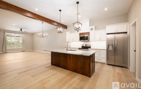 A modern kitchen with wooden floors and stainless steel appliances.