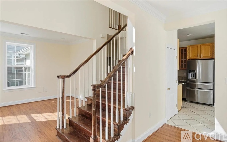 A wooden staircase with white railings leads to a kitchen area.