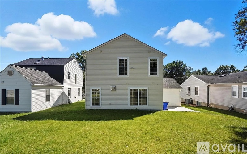 A white house with a black roof is surrounded by other similar houses.